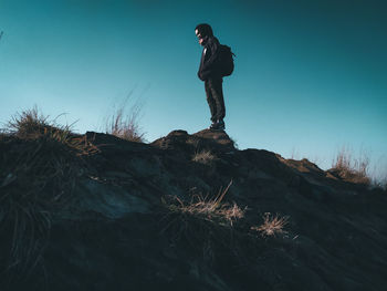 Low angle view of man standing on rock against sky