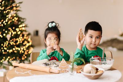 Asian kids brother and sister in pajamas prepare festive food for the christmas holiday at home