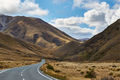 Road leading towards mountains against sky