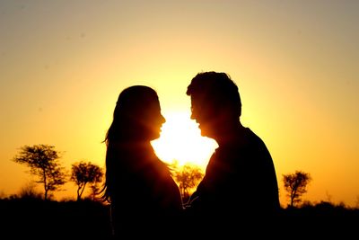 Silhouette friends standing against clear sky during sunset