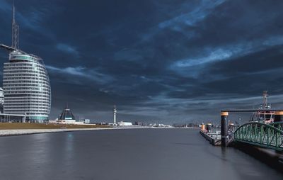 Illuminated bridge over river against sky at night