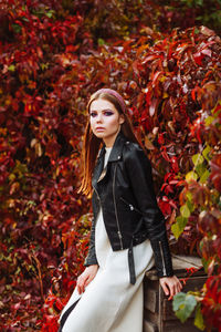 Portrait of beautiful young woman standing against trees