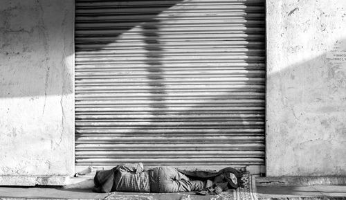 Man sleeping on road against closed shutter