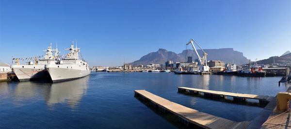 Sailboats moored at harbor against clear sky