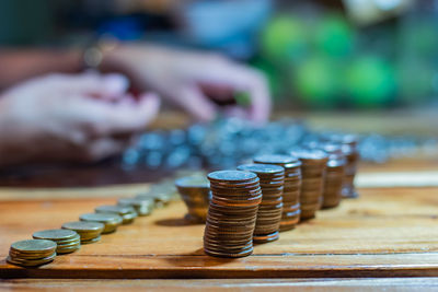 Cropped hand of woman counting coins while stacking on table