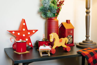 Christmas decor in the house, a wooden horse-gurney, a mug with cocoa, stars and a house