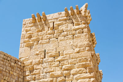 Low angle view of stone wall against clear blue sky