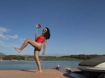 Full length of woman standing on beach against clear blue sky