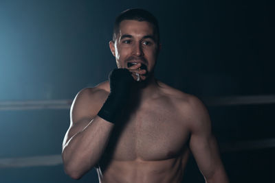 Muscular boxer looking away in ring