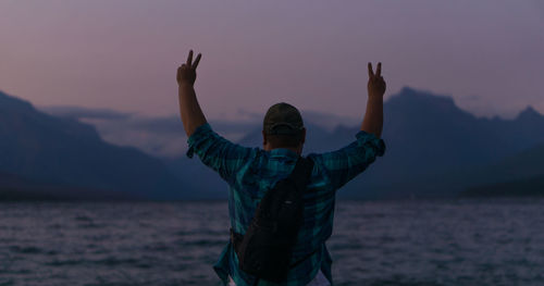 Man standing by sea against sky during sunset