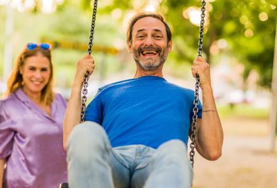 Portrait of young woman swinging at playground