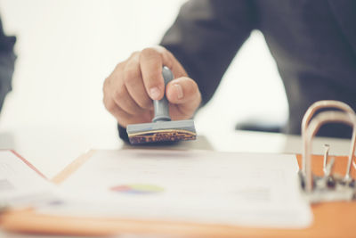 Midsection of lawyers holding rubber stamp at desk in office