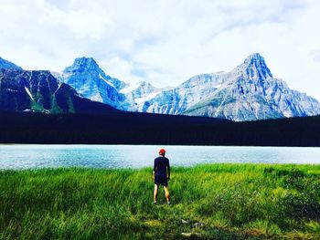 Rear view of man standing by lake against mountain at banff national park