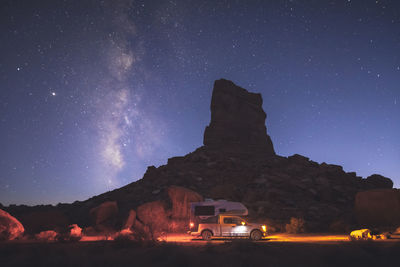 A small pickup rv is on a camping spot under the milky way