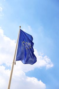 Low angle view of flag waving against blue sky