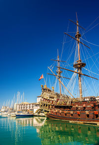 Sailboats moored in sea against clear blue sky