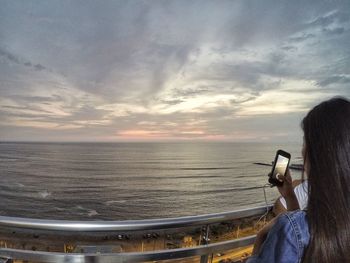 Rear view of man looking at sea against sky