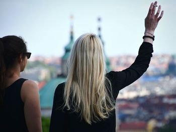 Rear view of female friends against cityscape against sky