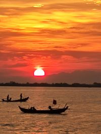 Silhouette people in boat in sea during sunset