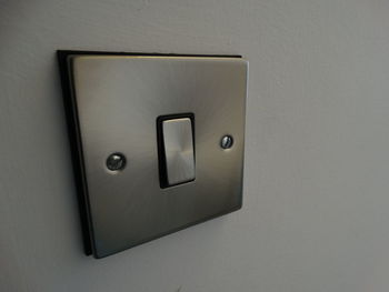 Close-up of silver electric switch on wall