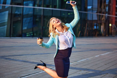 Full length of a young woman using phone in city