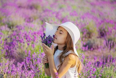 Girl smelling lavender flowers in field
