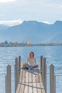 Adult young woman siting in small wooden dock entering lake geneva