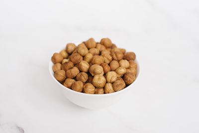 Close-up of peanuts in bowl on white background