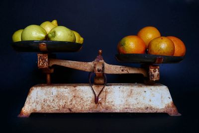 Close-up of fruits of old weight scale against colored background