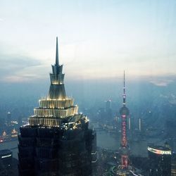 Communications tower in city against sky