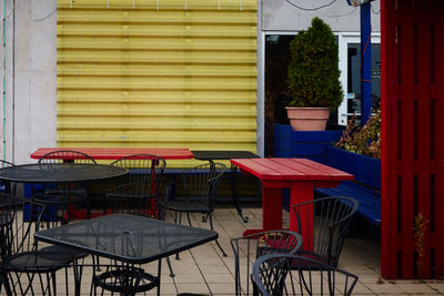 Empty chairs and tables at sidewalk cafe against buildings in city