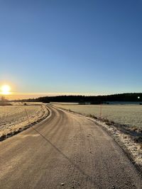Road by land against clear blue sky