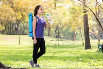 Full length of woman drinking water in park