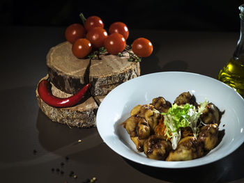 Close-up of food in plate by tomatoes and chili pepper on table