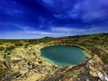 Scenic view of landscape against abandoned mine and blue sky