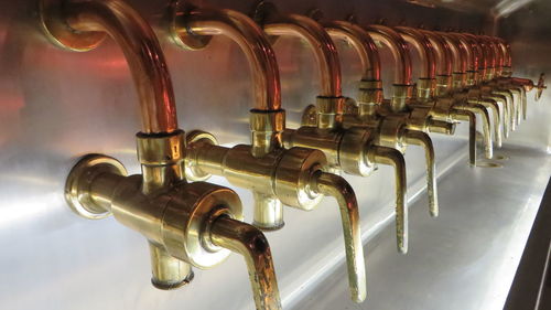 Row of gold colored beer taps at bar