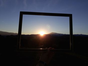 Hand against sky during sunset