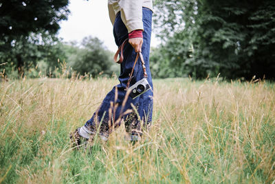 Woman holding camera while walking on grass in public park