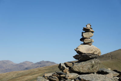 Stack of stones on rock against sky