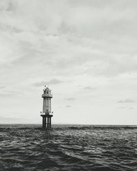 Lighthouse by sea against sky