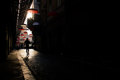 Silhouette man walking in dark alley