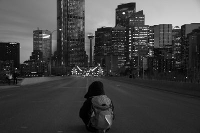 Rear view of man walking on road in city