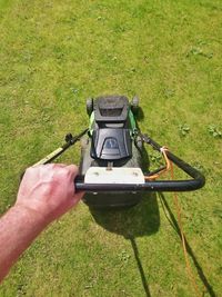 Cropped image of man using lawn mover on grassy field