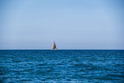 Sailboat sailing on sea against clear sky