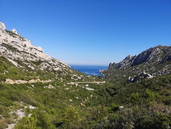 Scenic view of sea and mountains against clear blue sky