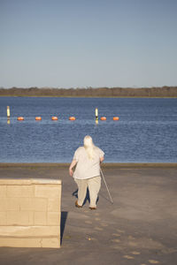 Rear view of woman looking at sea against clear sky