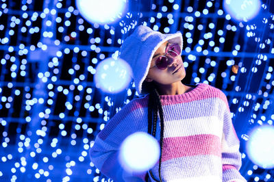 Joyful woman of color with a white beanie braided hairstyle and pink glasses enjoying the christmas 