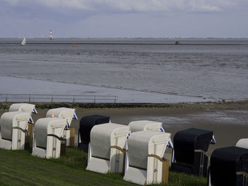 Hooded chairs at beach against sky