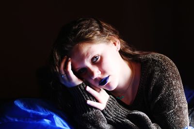 Portrait of beautiful young woman against black background