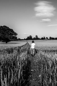 Rear view of person standing on field against sky